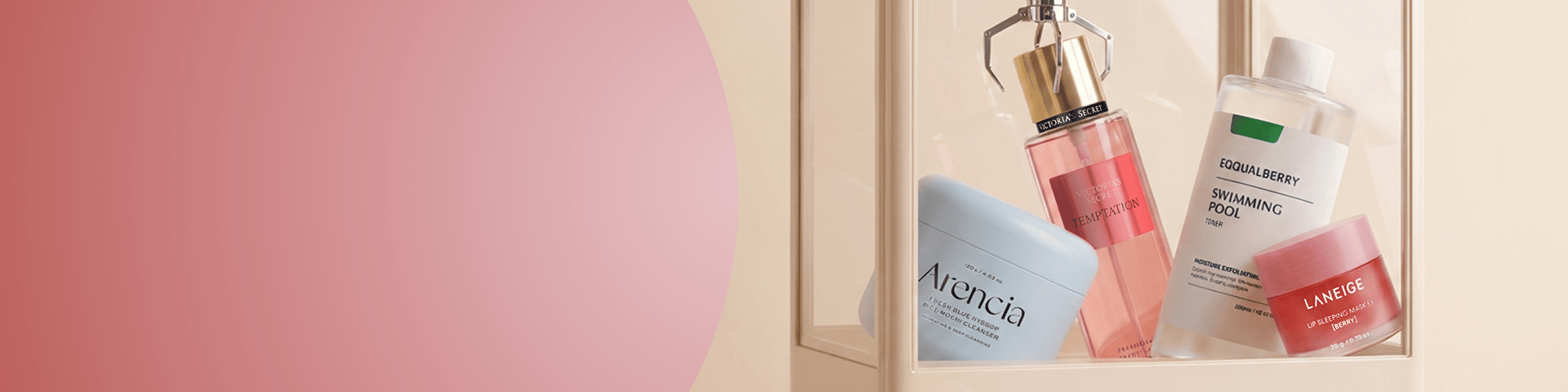Szklana gablotka z kosmetykami viralowych marek: mgiełka Victoria’s Secret Temptation, żel do mycia Arencia, tonik Equalberry Swimming Pool i maska do ust Laneige. Baner promujący popularne hity beauty do odkrycia w drogerii online.
